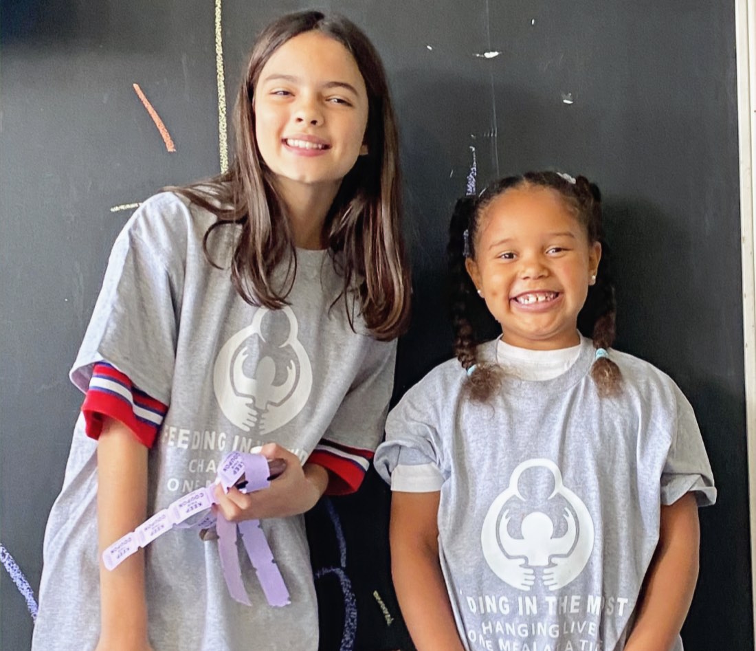 Two young girls smiling in Feeding In The Midst t-shirts
